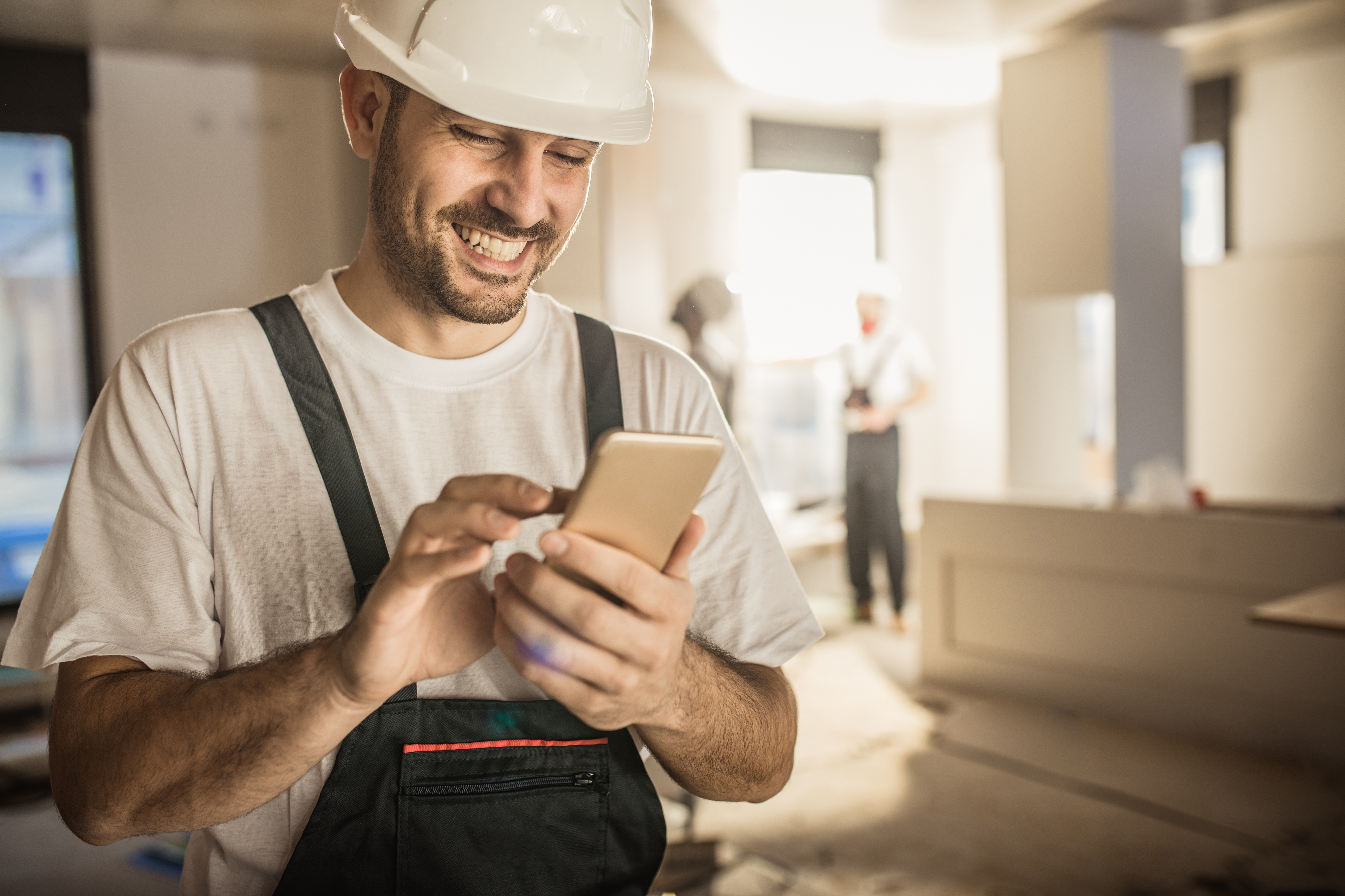 Handwerker mit Smartphone auf Baustelle – nutzt digitale Lösungen von directpool zur einfachen Projektabwicklung und effizienten Kommunikation im Handwerk.